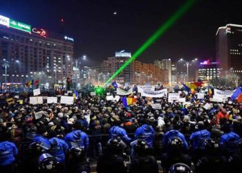 Romanian riot police stand guard as people demonstrate against controversial decrees to pardon corrupt politicians